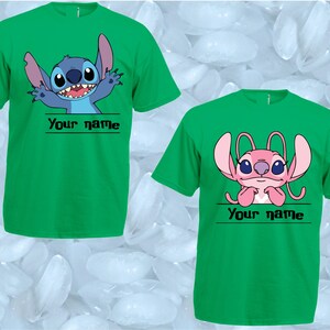 Peut inclure: Deux t-shirts verts avec des personnages de dessins anim&eacute;s. L'un pr&eacute;sente un personnage bleu, l'autre un personnage rose, tous deux avec le texte "Your name" en dessous. Les deux ont des manches courtes.