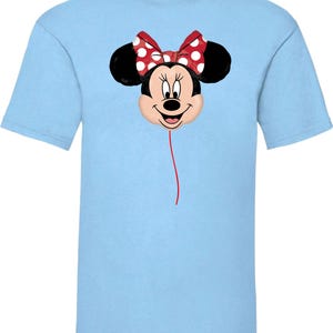 K&ouml;nnte beinhalten: Hellblaues T-Shirt mit einem Minnie Mouse-Motiv. Das Design zeigt Minnie's Gesicht, eine rote Schleife mit wei&szlig;en Punkten und schwarze Ohren. Eine rote Linie erstreckt sich vom Gesicht und erzeugt einen Ballon-Effekt. Das T-Shirt ist kurz&auml;rmelig.