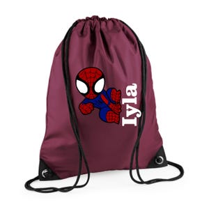 Puede incluir: Una bolsa de cord&oacute;n burdeos con un dise&ntilde;o de dibujos animados de Spider-Man en rojo, azul y blanco. El nombre "Iyla" est&aacute; impreso verticalmente en blanco. La bolsa tiene cordones y ojales negros.