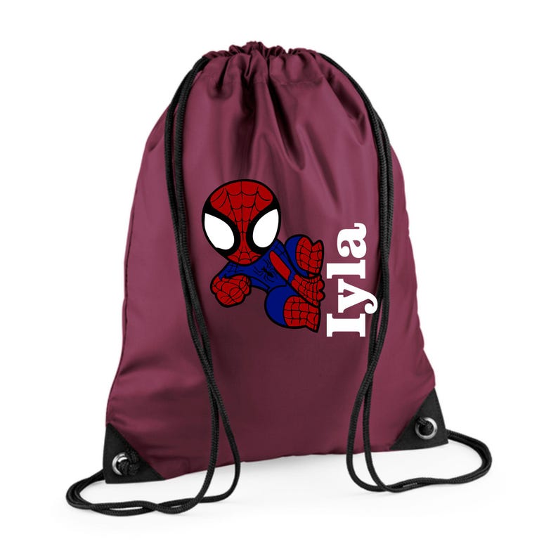 Puede incluir: Una bolsa de cord&oacute;n burdeos con un dise&ntilde;o de dibujos animados de Spider-Man en rojo, azul y blanco. El nombre "Iyla" est&aacute; impreso verticalmente en blanco. La bolsa tiene cordones y ojales negros.