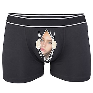 May include: Black boxer shorts with a graphic print of a woman's face peeking out from a ripped opening.