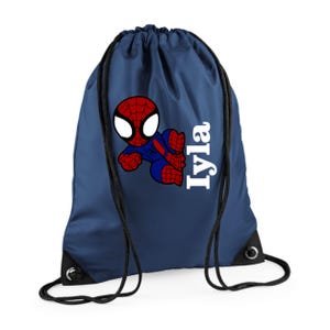 Puede incluir: Mochila con cord&oacute;n de color azul marino con un dibujo animado de Spider-Man en rojo, azul y blanco. El nombre "Iyla" est&aacute; impreso en blanco, verticalmente. La mochila tiene cordones y ojales negros.