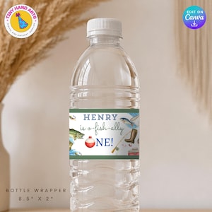 Może przedstawiać: Przezroczysta plastikowa butelka wody z białą zakrętką. Butelka ma zielono-białą etykietę z napisem "HENRY is o-fish-ally ONE!" z ilustracjami o tematyce wędkarskiej. Owińcie butelkę o wymiarach 21,6 cm x 5,1 cm.