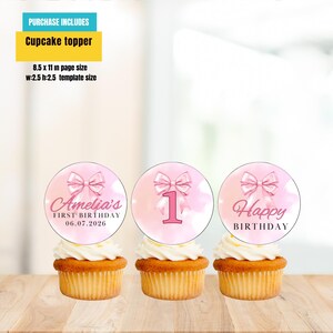 Puede incluir: Tres cupcakes con adornos rosas y blancos. Un adorno dice "Amelia's FIRST BIRTHDAY 06.07.2026", otro tiene un "1" rosa, y el &uacute;ltimo dice "Happy BIRTHDAY". La imagen incluye el texto "PURCHASE INCLUDES Cupcake topper".