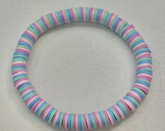 May include: A pastel-colored bracelet made of stacked, round beads. The beads are in shades of pink, blue, and white.