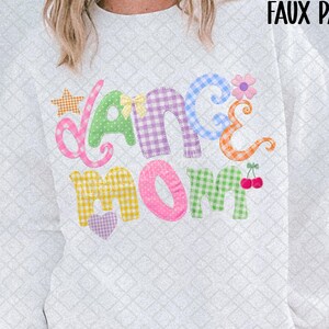 Könnte beinhalten: Weißes Sweatshirt mit dem Schriftzug "DANCE MOM" in bunten Patchwork-Buchstaben. Das Design beinhaltet einen Stern, eine Blume und Kirschen. Der Text "PNG FILE FAUX PATCHWORK" ist ebenfalls sichtbar.