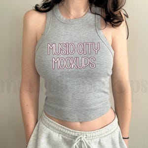 Puede incluir: Un top de tirantes gris con el texto "Music City Mockups" impreso en rosa en la parte delantera.