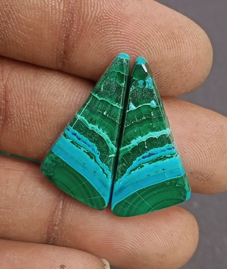 May include: A pair of green and blue gemstone cabochons with a triangular shape. The cabochons have a layered pattern with shades of green and blue.
