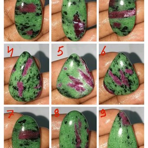 May include: Nine polished oval and teardrop-shaped gemstones. Each stone features a green base with black speckles and vibrant red inclusions. The gemstones are displayed against a neutral background, showcasing their natural beauty and unique patterns.