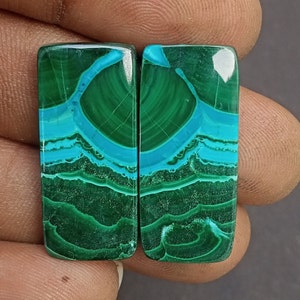 May include: Pair of green and blue malachite cabochons, each with a unique pattern of swirling lines and a smooth, polished surface. These cabochons are ideal for jewelry making or other craft projects.