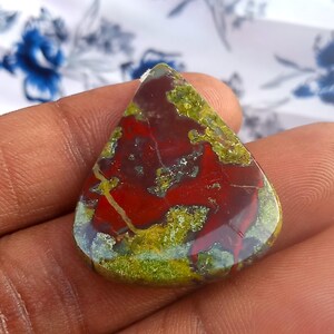Puede incluir: Un cabuj&oacute;n de jaspe rojo, verde y marr&oacute;n en forma de l&aacute;grima. La piedra tiene un patr&oacute;n &uacute;nico y arremolinado y un acabado pulido.