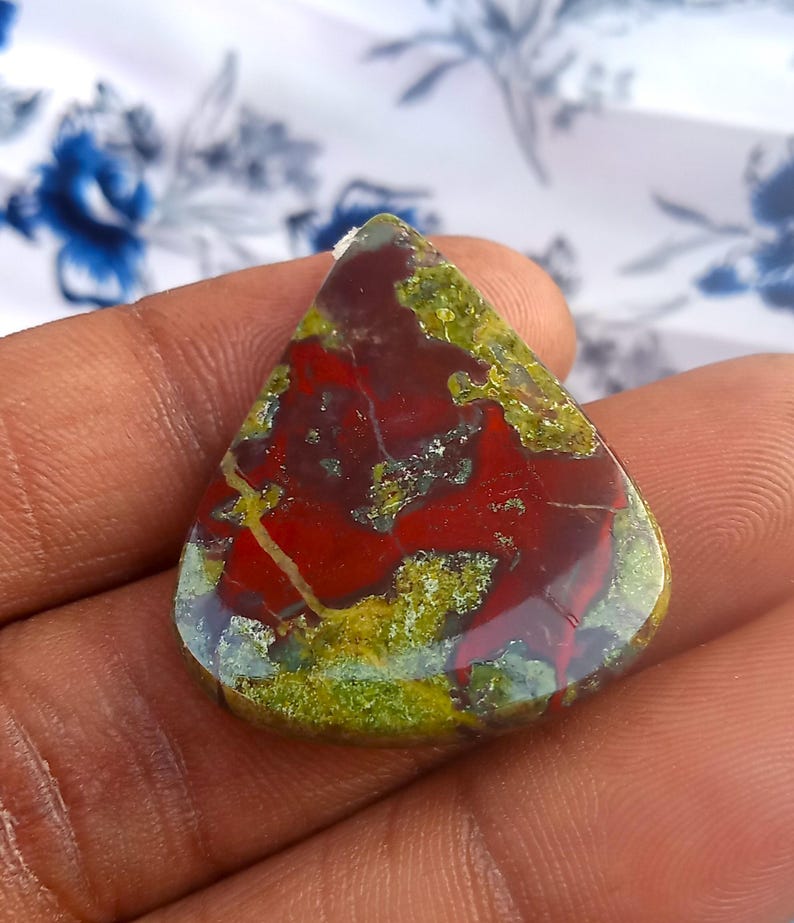Puede incluir: Un cabuj&oacute;n de jaspe rojo, verde y marr&oacute;n en forma de l&aacute;grima. La piedra tiene un patr&oacute;n &uacute;nico y arremolinado y un acabado pulido.