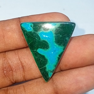 Könnte beinhalten: Ein dreieckiger grüner und blauer Edelstein mit einem einzigartigen Muster. Der Edelstein ist in Dreiecksform geschliffen und hat eine glatte, polierte Oberfläche.