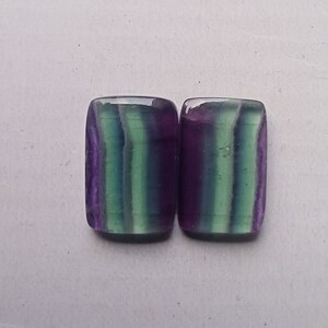 Puede incluir: Dos piedras preciosas de fluorita rectangulares con rayas verdes, moradas y blancas. Las piedras est&aacute;n talladas y pulidas.