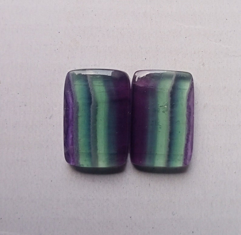 Puede incluir: Dos piedras preciosas de fluorita rectangulares con rayas verdes, moradas y blancas. Las piedras est&aacute;n talladas y pulidas.