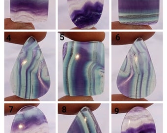 Può includere: Nove cabochon di fluorite in varie forme e dimensioni, che mostrano una bellissima miscela di colori viola, bianco e verde. I cabochon sono disposti in una griglia, con ciascuno numerato da 1 a 9.