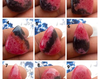 Puede incluir: Nueve piedras preciosas de rodocrosita pulidas en varias formas. Las piedras muestran una mezcla de colores rosa y negro. Las formas incluyen redonda, cuadrada, rectangular, de lágrima y ovalada. Las piedras preciosas se muestran sobre un fondo neutro.