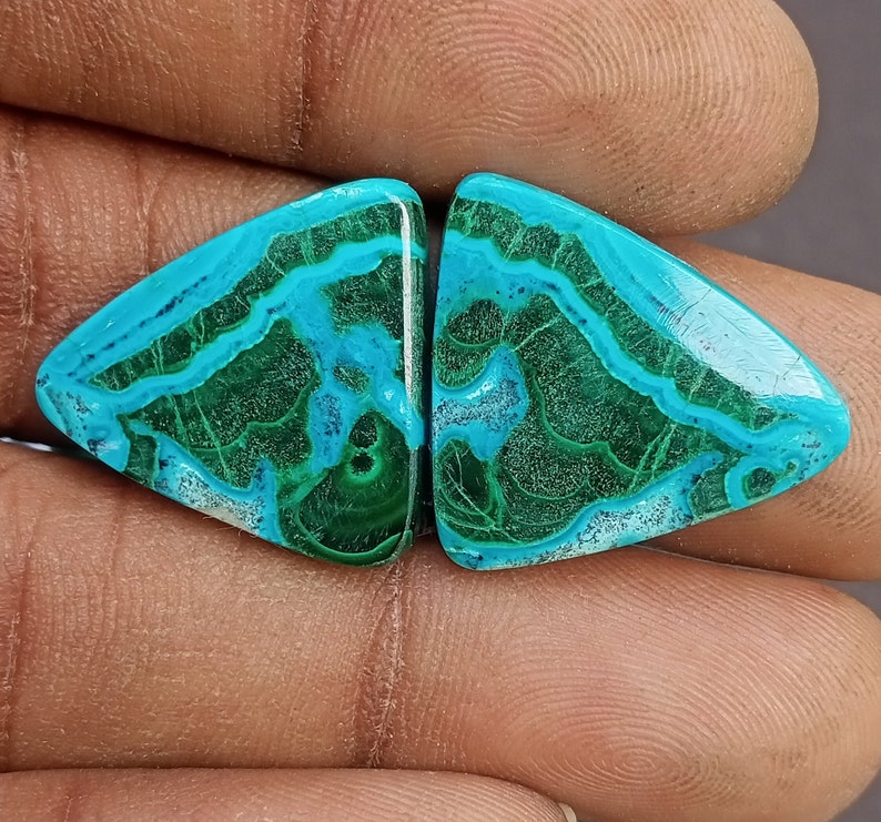 May include: A pair of green and blue malachite cabochons, cut into a triangular shape. The stones have a unique, swirling pattern.