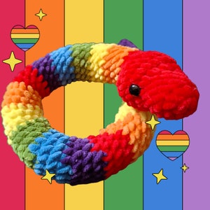 May include: A rainbow crocheted snake toy in the shape of a circle. The snake is made of different coloured yarn, including red, orange, yellow, green, blue, and purple. The snake is sitting on a rainbow background.