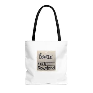 May include: White tote bag with black handles featuring a vintage ticket stub with the text "BOWIE NYC 6-11 Roseland"
