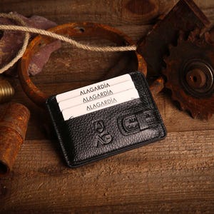 May include: A white ceramic mug with a black handle and the text "But First, Coffee" in a bold, black font. The mug is set against a blurred background, suggesting a cozy setting.