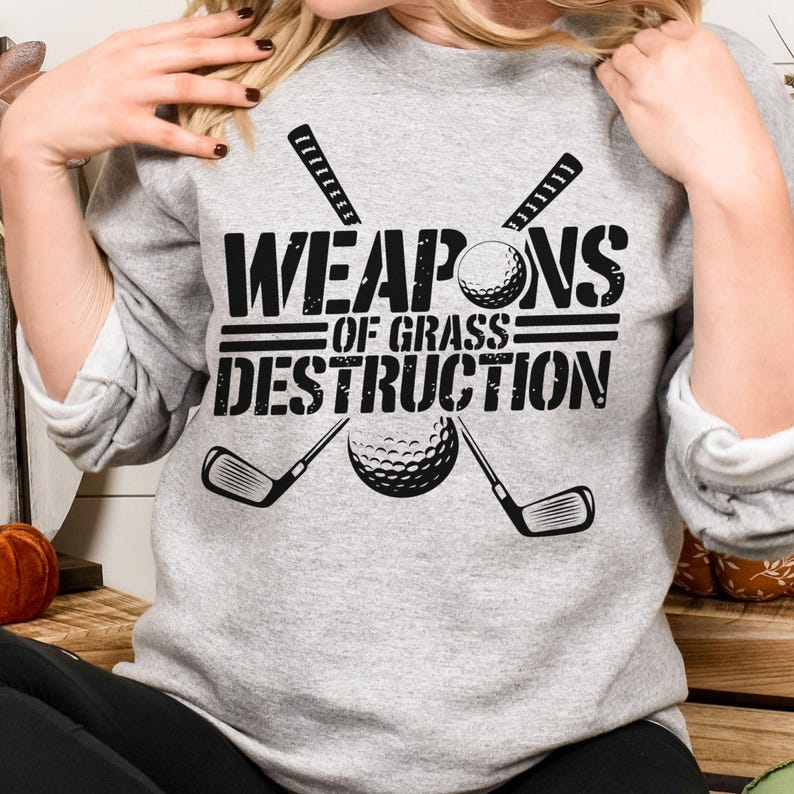 May include: Gray sweatshirt with a black graphic design that says "Weapons of Grass Destruction" with a golf ball and two golf clubs.
