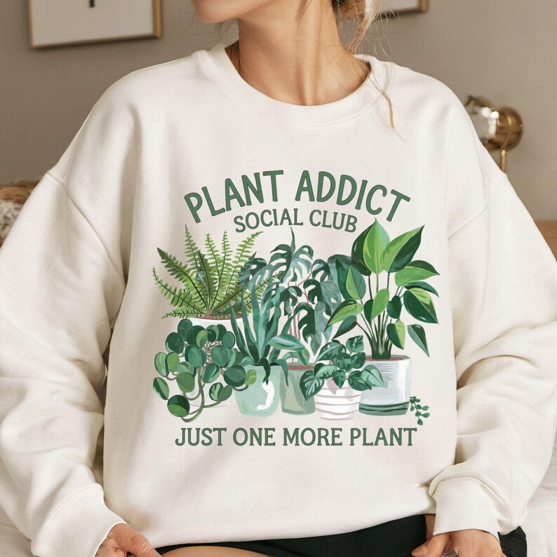 May include: White sweatshirt with a green graphic of potted plants and the text "Plant Addict Social Club Just One More Plant".