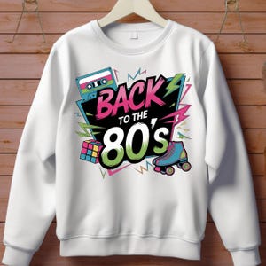 May include: White sweatshirt with a colorful graphic print that says "Back to the 80's". The graphic includes a cassette tape, a Rubik's Cube, and roller skates.