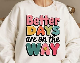 May include: White sweatshirt with a colorful graphic that says "Better Days are on the Way" with a smiley face in the word "Way".