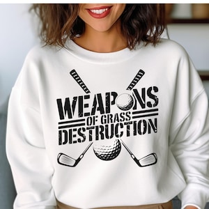 May include: White sweatshirt with black text that reads "Weapons of Grass Destruction" with a golf club and golf ball graphic.
