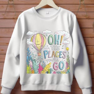 May include: White sweatshirt with a colourful hot air balloon, clouds, and the text "Oh! The Places You'll Go" printed on the front.