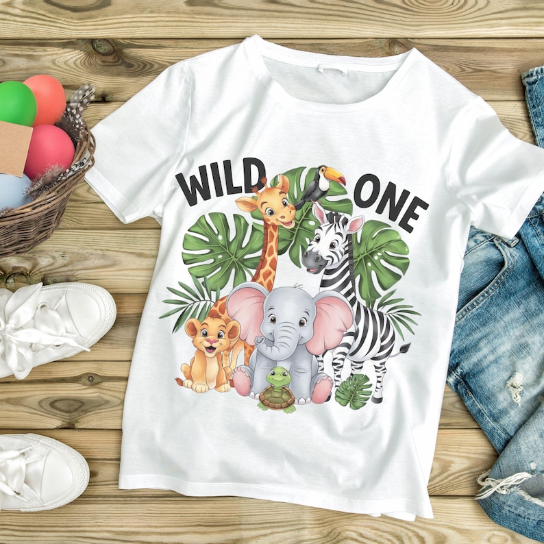 May include: White t-shirt with a graphic of a giraffe, zebra, elephant, lion, and turtle. The text "WILD ONE" is printed on the shirt.
