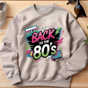 May include: A beige sweatshirt with a graphic print of a cassette tape, a Rubik's cube, roller skates, and the text "Back to the 80's".