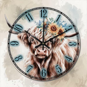 Op de afbeelding: Een ronde klok met een bruine en witte hooglandkoe met een bloemenkrans van zonnebloemen en blauwe bloemen. De wijzerplaat van de klok heeft zwarte Romeinse cijfers en zwarte wijzers.