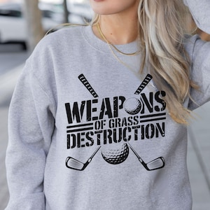 May include: Gray sweatshirt with a black graphic design that says "Weapons of Grass Destruction" with a golf club and golf ball.