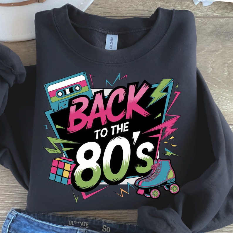 May include: Black sweatshirt with a colorful graphic design featuring a cassette tape, a Rubik's cube, roller skates, and the text "Back to the 80's".