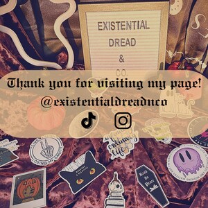 May include: A collection of stickers with diverse designs, such as a black cat, a coffin, and a melting ghost. The image also displays a sign that reads "EXISTENTIAL DREAD & CO." and the text "Thank you for visiting my page! @existentialdreadnco."