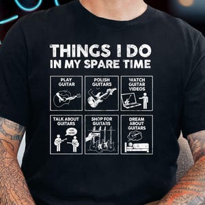 May include: Black t-shirt with the text "THINGS I DO IN MY SPARE TIME" and illustrations of guitar-related activities. The activities include playing, polishing, and watching guitar videos, talking about, shopping for, and dreaming about guitars.