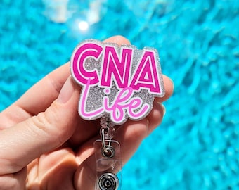 May include: A silver glitter and pink "CNA Life" badge reel with a clear retractable badge holder.