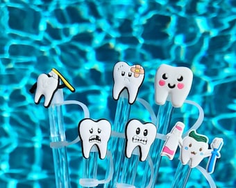 May include: A set of clear plastic straw covers featuring various white tooth-shaped charms. The charms include a tooth brushing, a tooth with a bandage, a smiling tooth, two teeth with worried expressions, and a tooth holding a toothbrush.