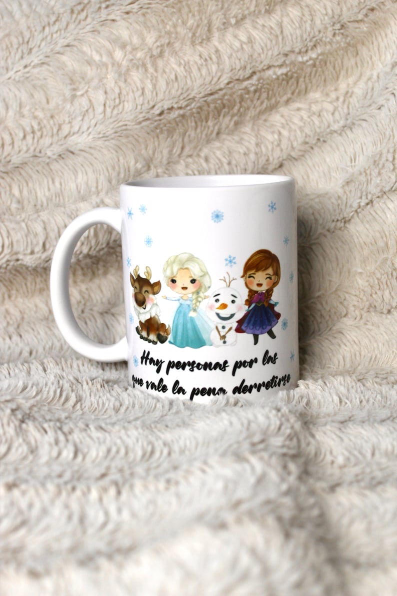 Puede incluir: Taza de cer&aacute;mica blanca con un dise&ntilde;o que presenta personajes de dibujos animados de la pel&iacute;cula Frozen. Los personajes incluyen a Elsa, Anna, Olaf y Sven. La taza tiene un patr&oacute;n de copo de nieve azul y el texto "Hay personas por las que vale la pena derretirse".