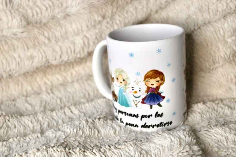 Puede incluir: Taza de cer&aacute;mica blanca con un dise&ntilde;o que presenta a los personajes de la pel&iacute;cula Frozen. Los personajes son Elsa, Anna y Olaf. La taza tiene un patr&oacute;n de copo de nieve azul y blanco y el texto "No te preocupes por las personas por las que la pena derretirse".