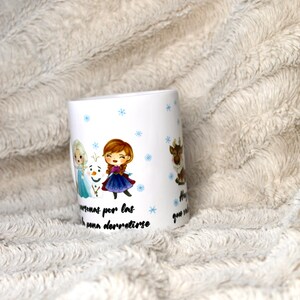 Puede incluir: Taza de cer&aacute;mica blanca con un dise&ntilde;o que presenta personajes de dibujos animados de la pel&iacute;cula Frozen. La taza tiene copos de nieve azules y el texto "Hay personas por las que vale la pena derretirse".