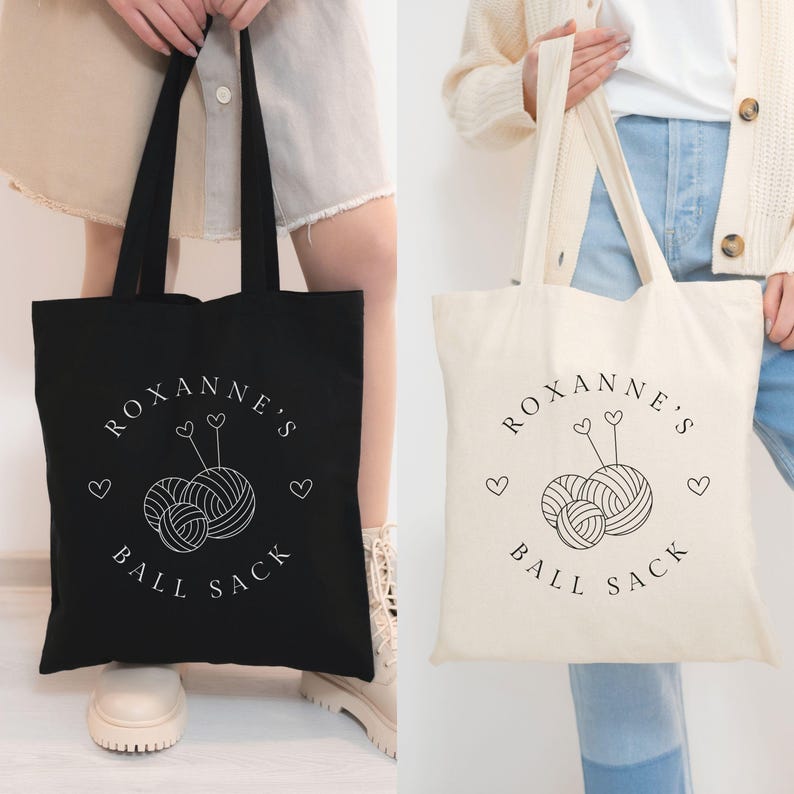 May include: Two tote bags with the text "Roxanne's Ball Sack" and a graphic of yarn balls and knitting needles. One bag is black and the other is natural canvas.