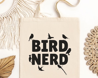 May include: A white canvas tote bag with black text that reads "BIRD NERD". The text is surrounded by a variety of black silhouette birds.