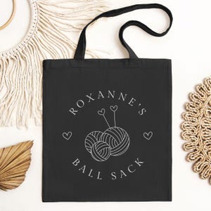 May include: Black canvas tote bag with white text that reads "Roxanne's Ball Sack" and a graphic of two yarn balls with needles and hearts.
