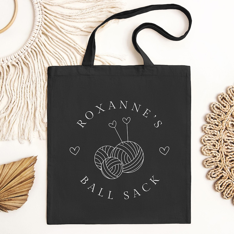 May include: Black canvas tote bag with white text that reads "Roxanne's Ball Sack" and a graphic of two yarn balls with needles and hearts.