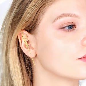 May include: Gold ear cuff with the name "Elena" written in cursive.