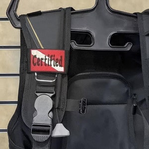 May include: Black scuba diving gear with a red patch that says "Certified" on it.