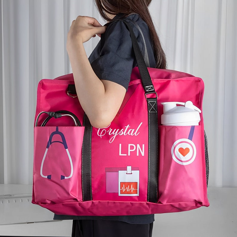 May include: Pink tote bag with black straps and a white water bottle in a side pocket. The bag has the text "Crystal LPN" and a heart with a stethoscope printed on it.